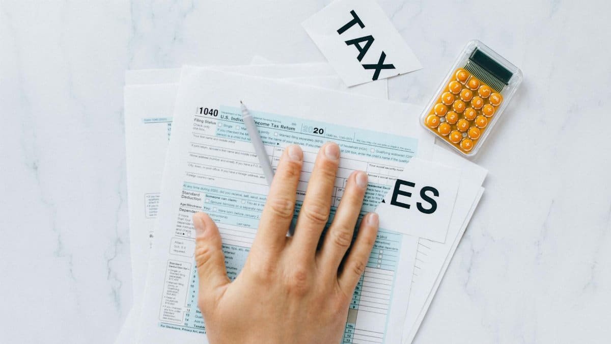 Close-up of a hand on tax form 1040 with a calculator on a desk.
