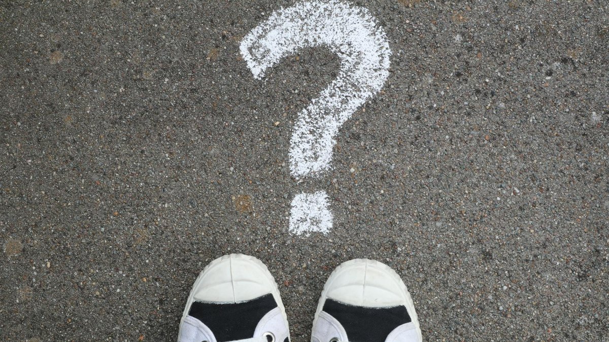 Sneakers on pavement with a chalk question mark, symbolizing curiosity or decisions.