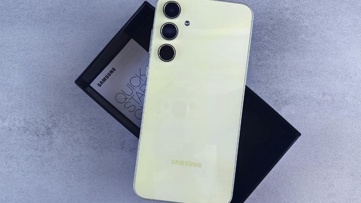 Yellow Samsung smartphone displayed on a gray surface with its box and quick start guide.