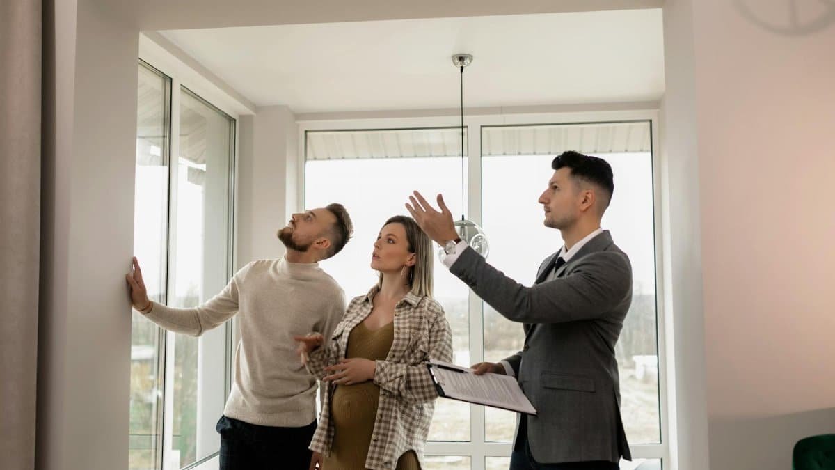 A young couple inspects a modern apartment with a real estate agent during a daytime viewing.