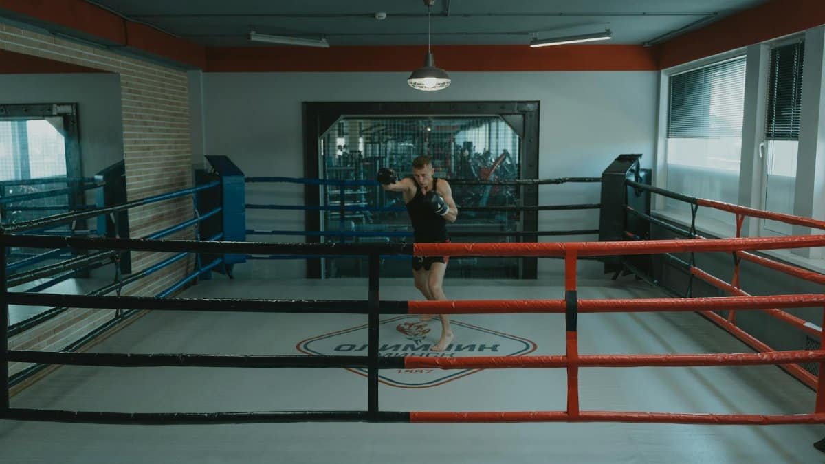 A professional boxer training alone in a well-lit boxing gym ring, showcasing focus and strength.