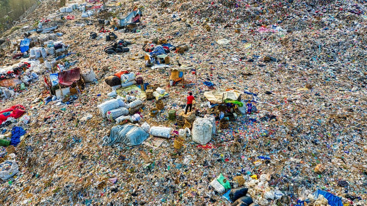 An aerial shot of a landfill site with scattered trash and environmental damage.