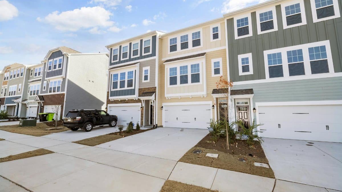A row of colorful modern townhouses in a suburban neighborhood on a sunny day.