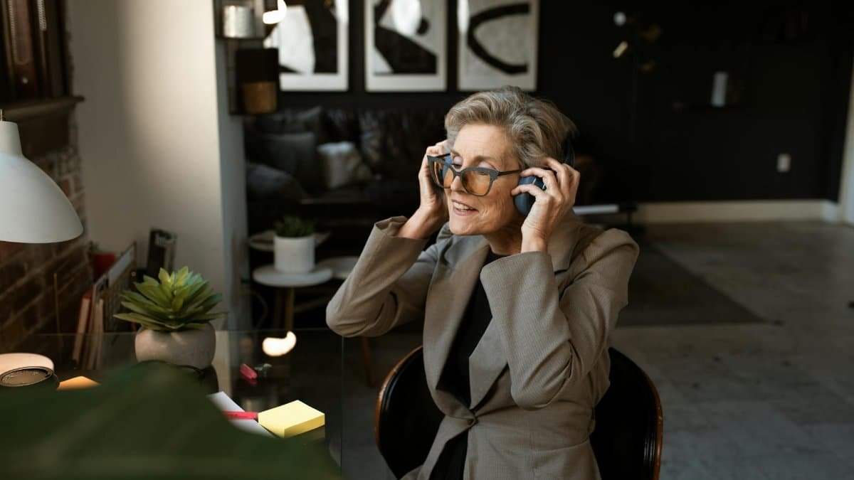 Mature woman enjoying music in modern home office setting. Stylish and relaxing.