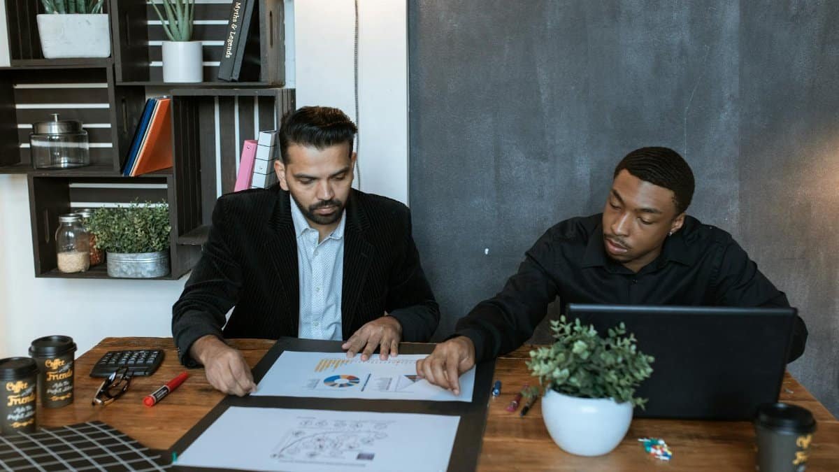 Two businessmen collaborating over financial charts in a modern office setting.