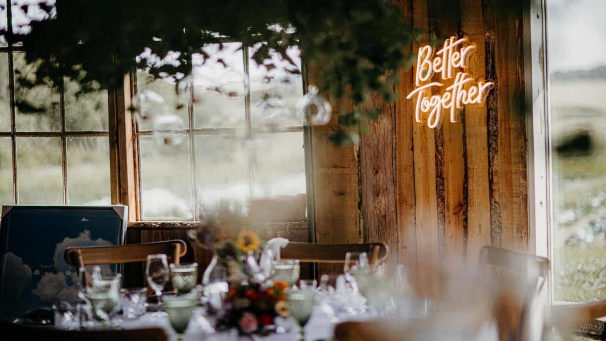 Warm and inviting dining area with a neon 'Better Together' sign and elegant place setting.