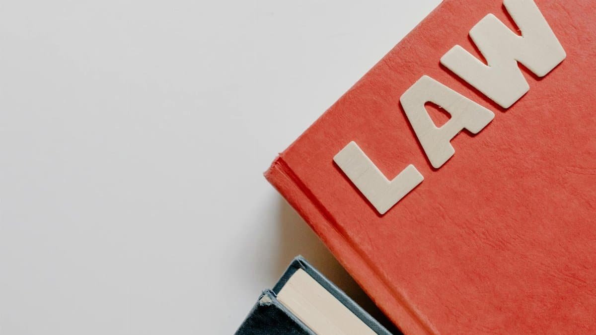 Red law textbook and dark book on white background, symbolizing education.
