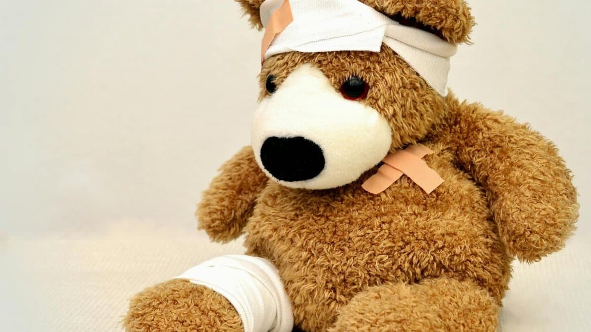 A brown teddy bear with bandages, depicting a playful take on injury recovery in a minimalist setting.