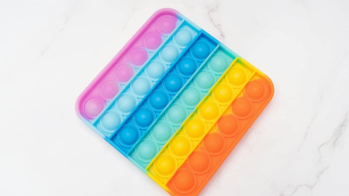 Rainbow Pop It fidget toy on a bright white surface, perfect for stress relief.