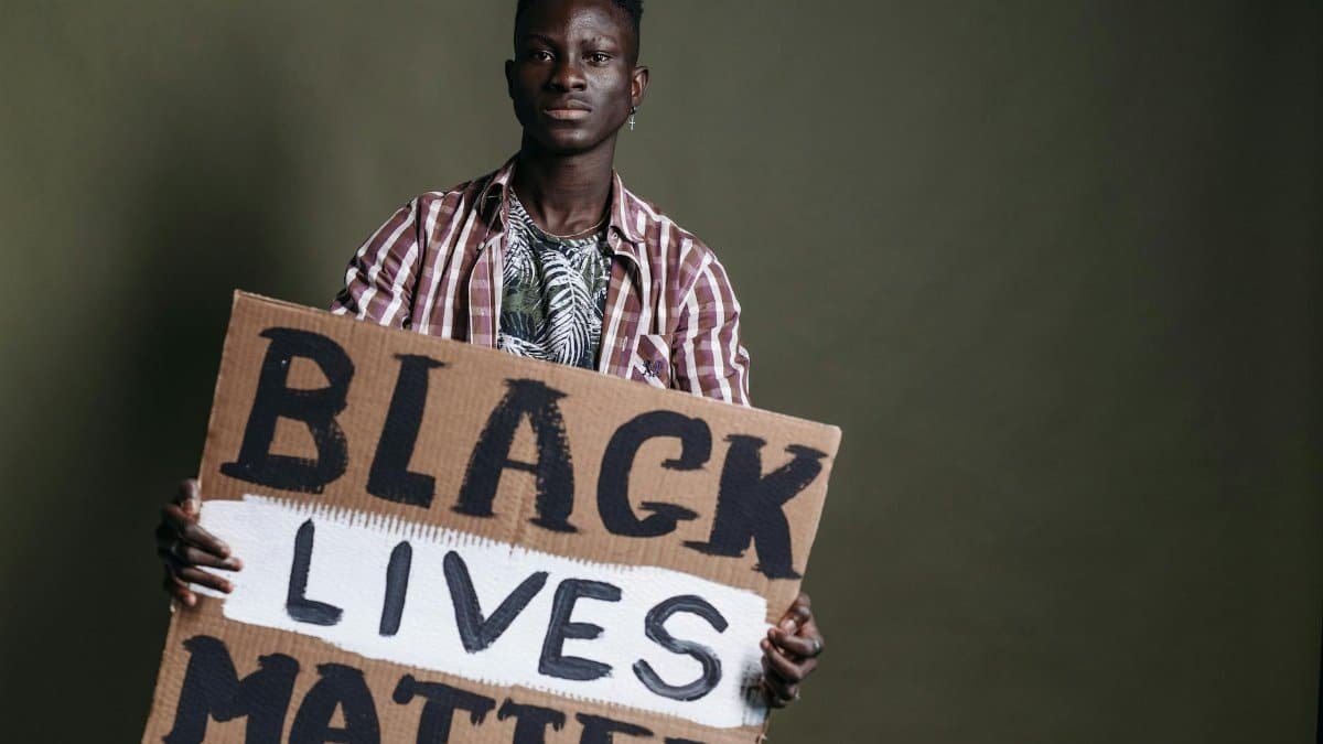 Portrait of a Black man holding a 'Black Lives Matter' sign, emphasizing human rights and activism.