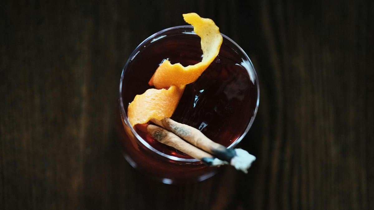 Top-down view of a cocktail garnished with orange peel and cinnamon stick, exuding sophistication.