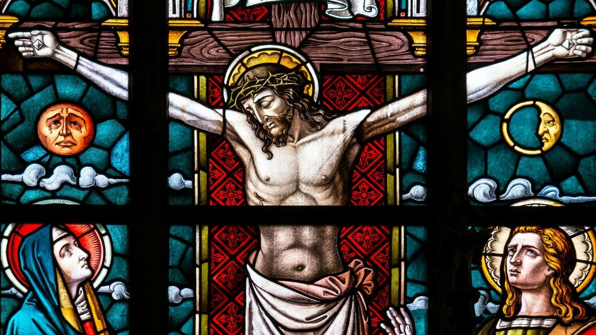 Detailed stained glass depiction of the crucifixion featuring Christ and religious icons.