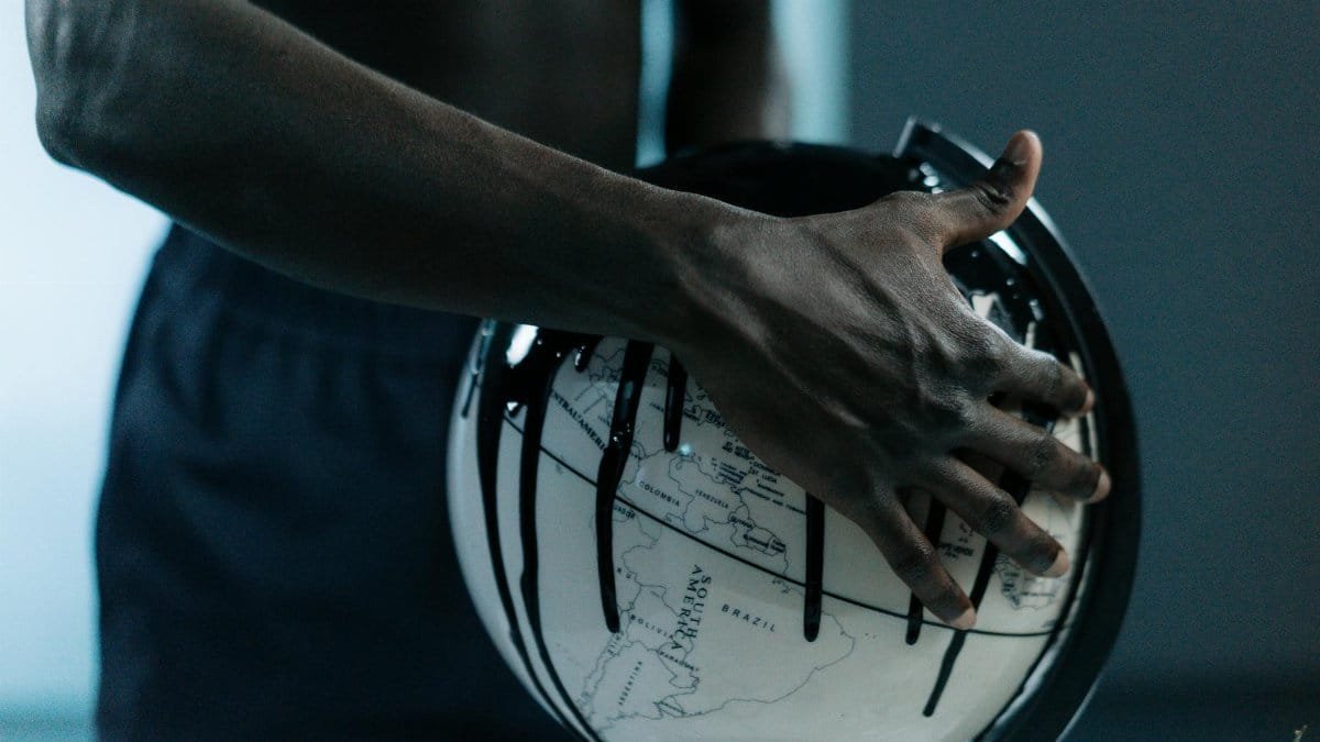 A hand holding a globe dripping with oil, symbolizing pollution and fossil fuels.