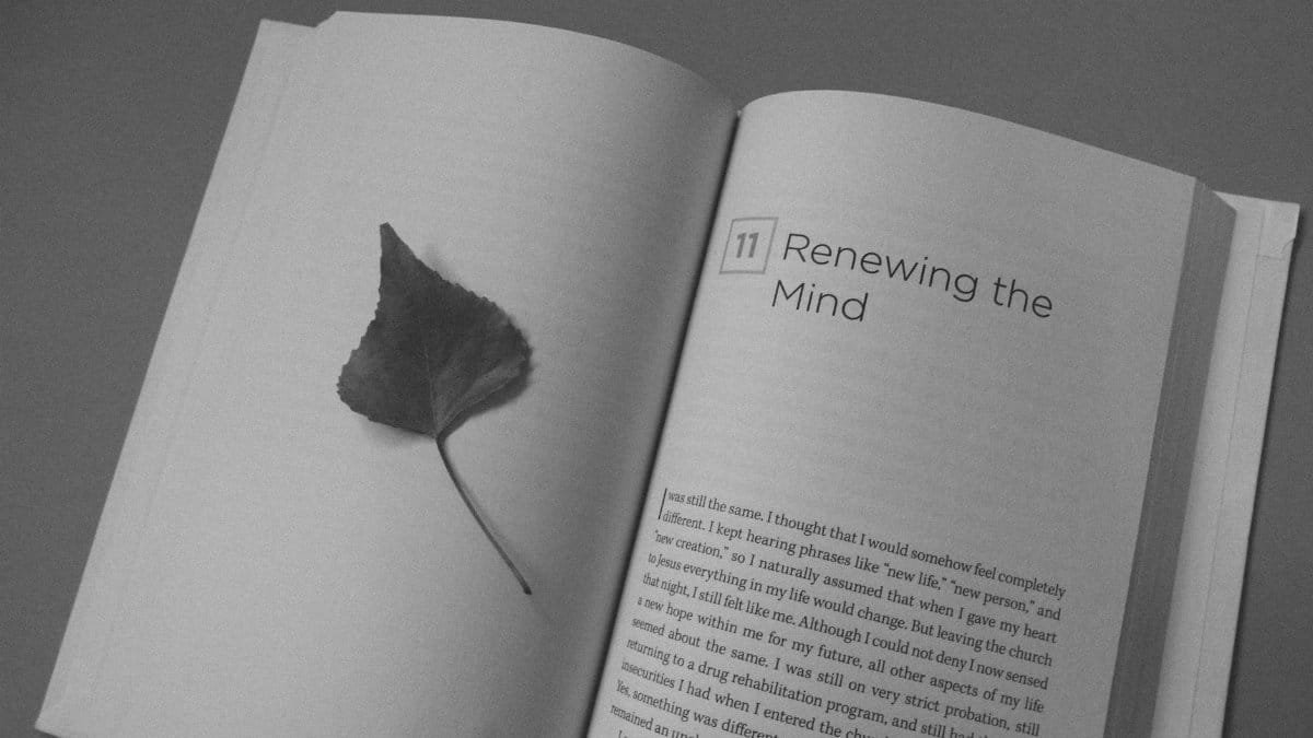 Open book with a leaf bookmark, showing the text 'Renewing the Mind'.