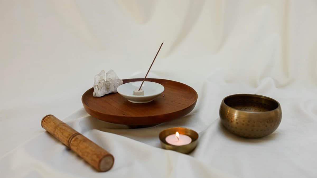 A calming meditation scene featuring an incense stick, candle, and Tibetan singing bowl for relaxation.