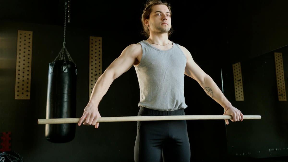 Athletic man exercising with stick in fitness gym, enhancing strength and coordination.