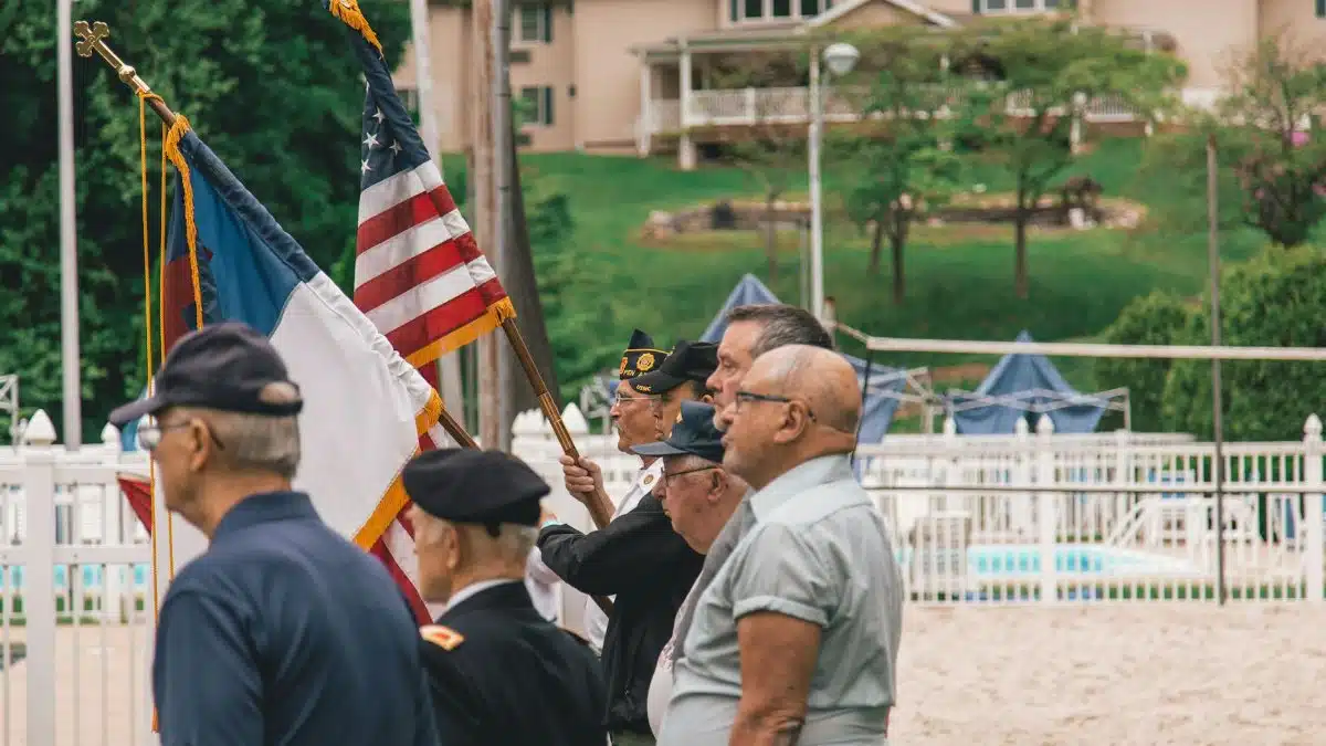 Group of veterans holding flags during an outdoor ceremony showing patriotism.