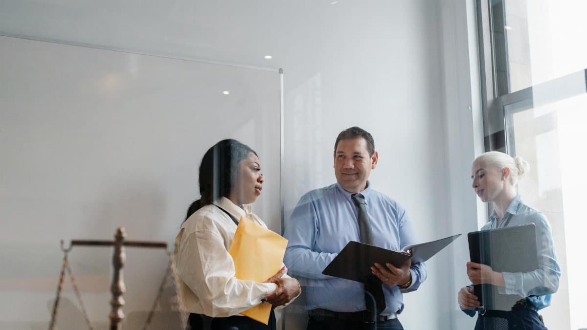 A diverse group of legal professionals discuss in a modern office setting, emphasizing collaboration and teamwork.