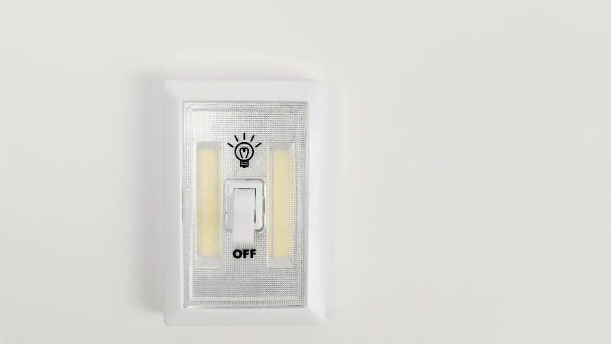 Minimalist light switch turned off on a plain white wall, offering ample copy space.