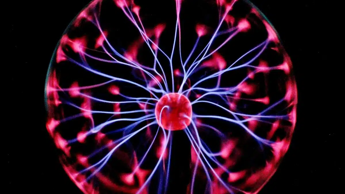 Close-up of a plasma globe with vibrant neon sparks against a dark background.