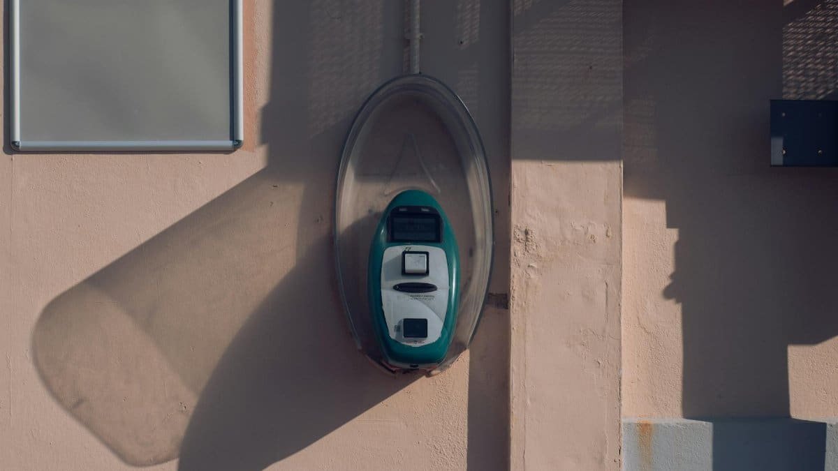 Ticket validator mounted on a wall in Avola, Sicily, casting a shadow in the afternoon light.