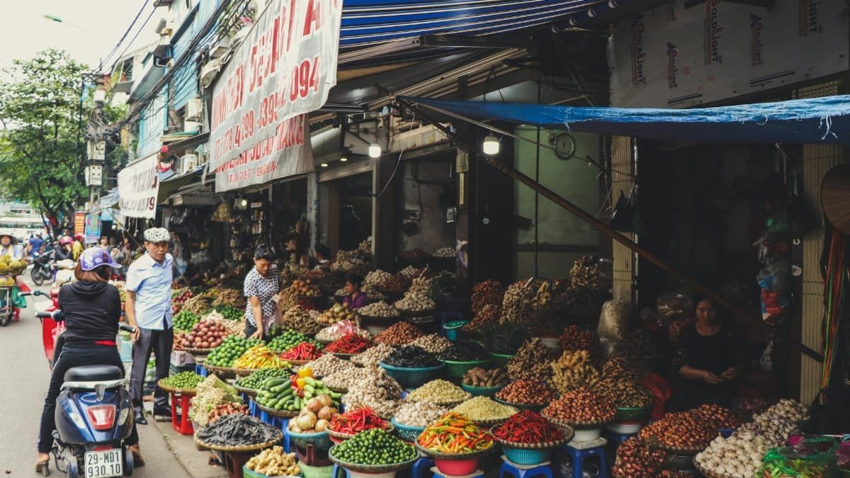 Bustling outdoor street market in Hanoi featuring colorful produce and local vendors.