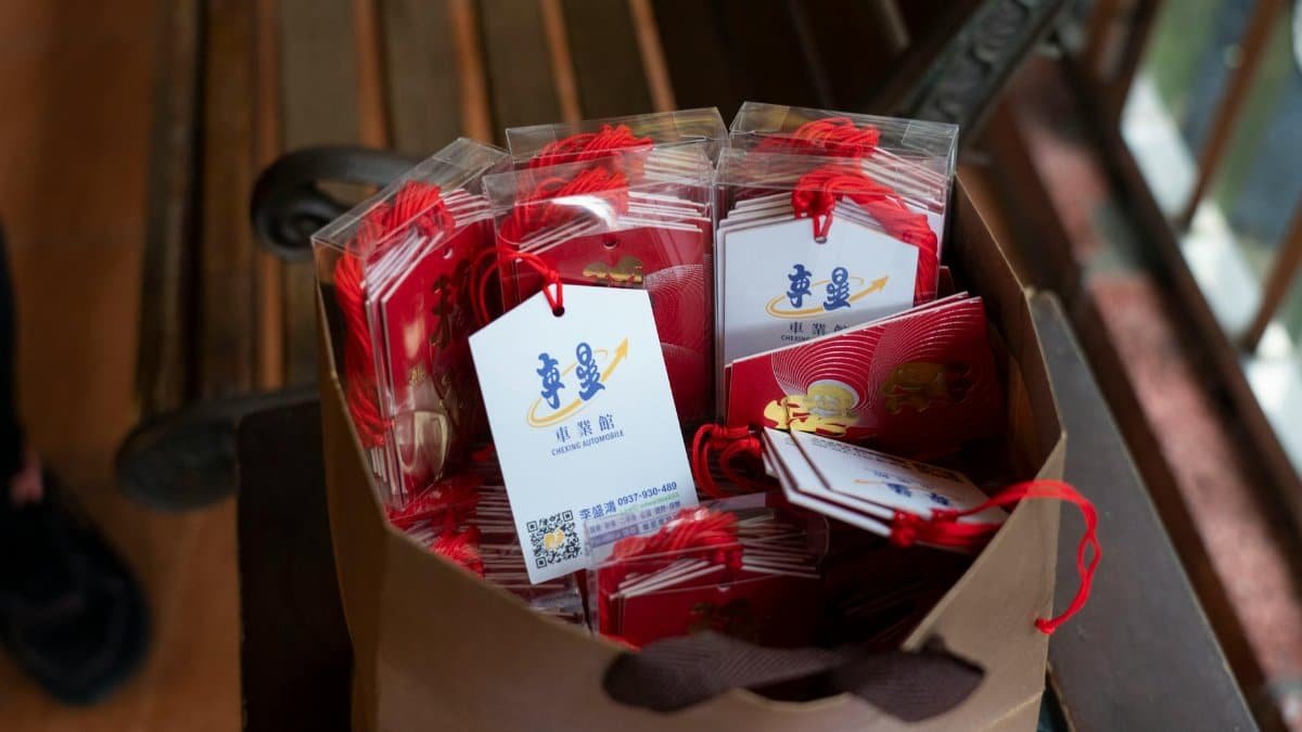 A brown paper bag filled with gift envelopes and decorative tags on a wooden bench.