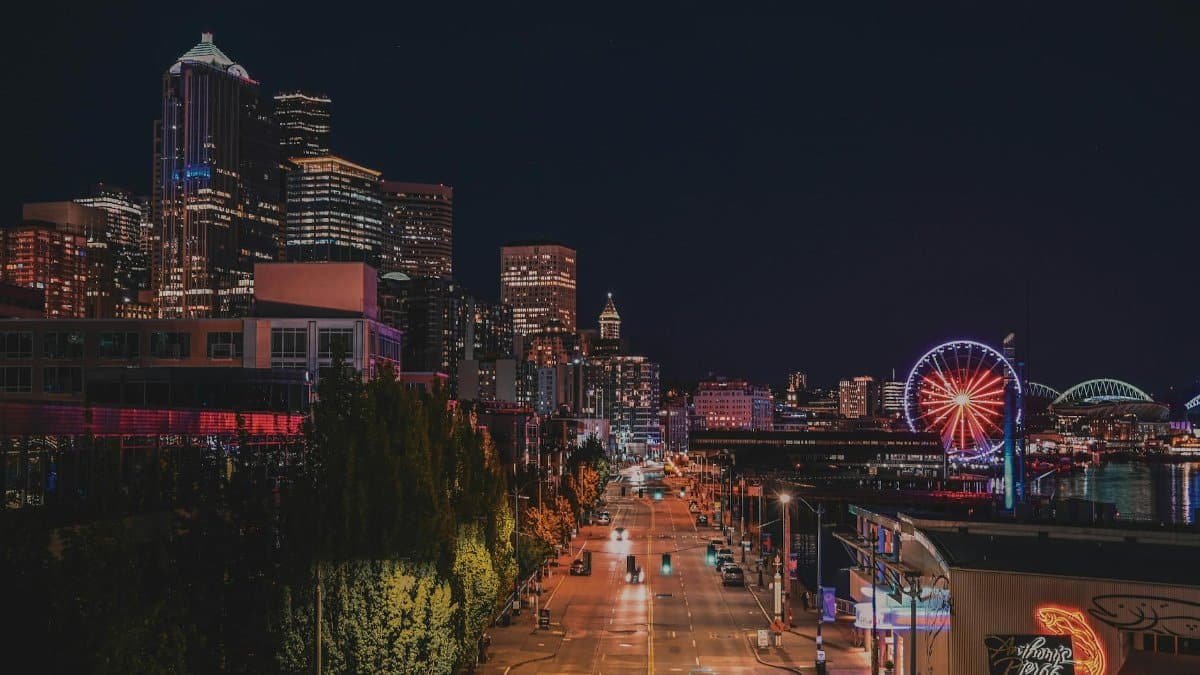 Seattle's vibrant skyline and iconic Ferris wheel illuminated under the night sky.