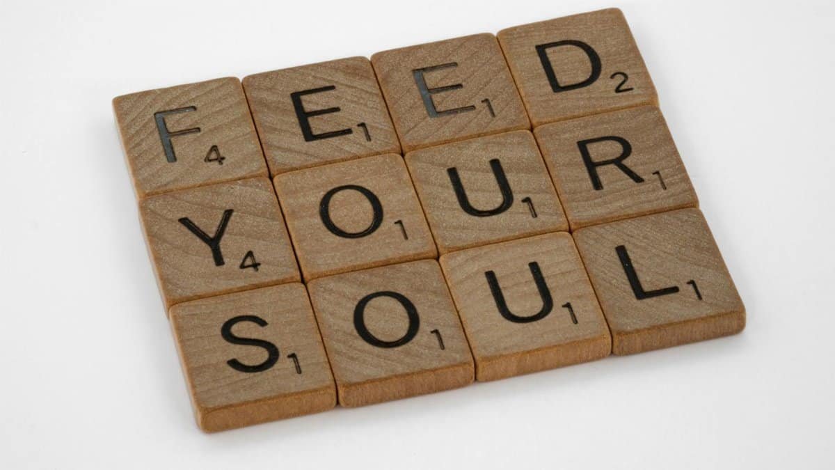 Close-up of Scrabble tiles spelling 'Feed Your Soul' on a white background.