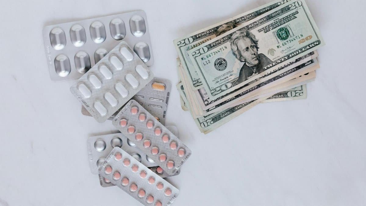 Blister packs of pills and US dollars on a white surface.