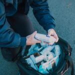 Emergency responder organizing medical supplies from a kit in an outdoor setting.