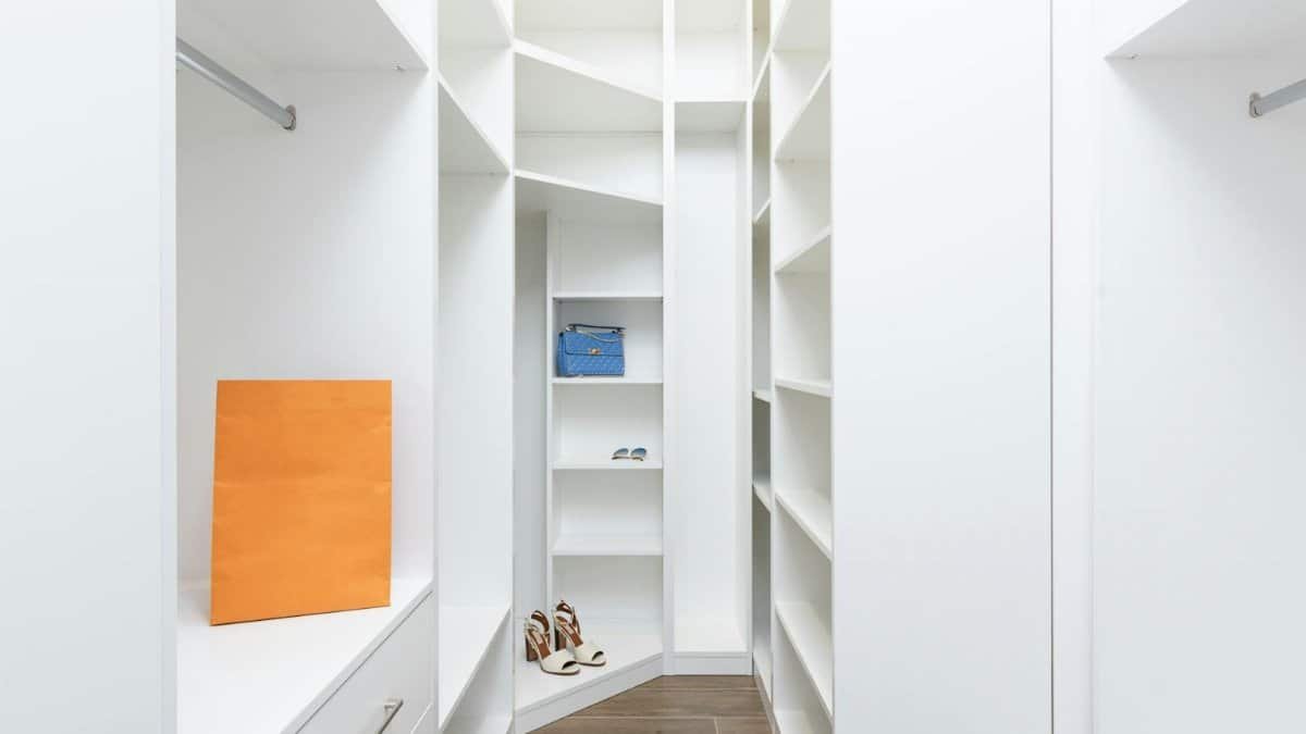 Perspective of white dressing room with rows of shelves and metal railings in modern design