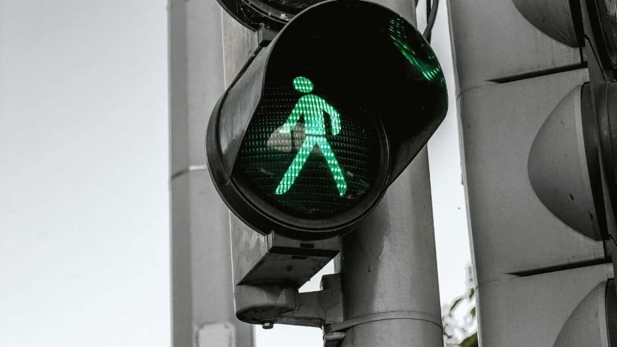 Close-up of a green pedestrian traffic signal indicating walk at an intersection.