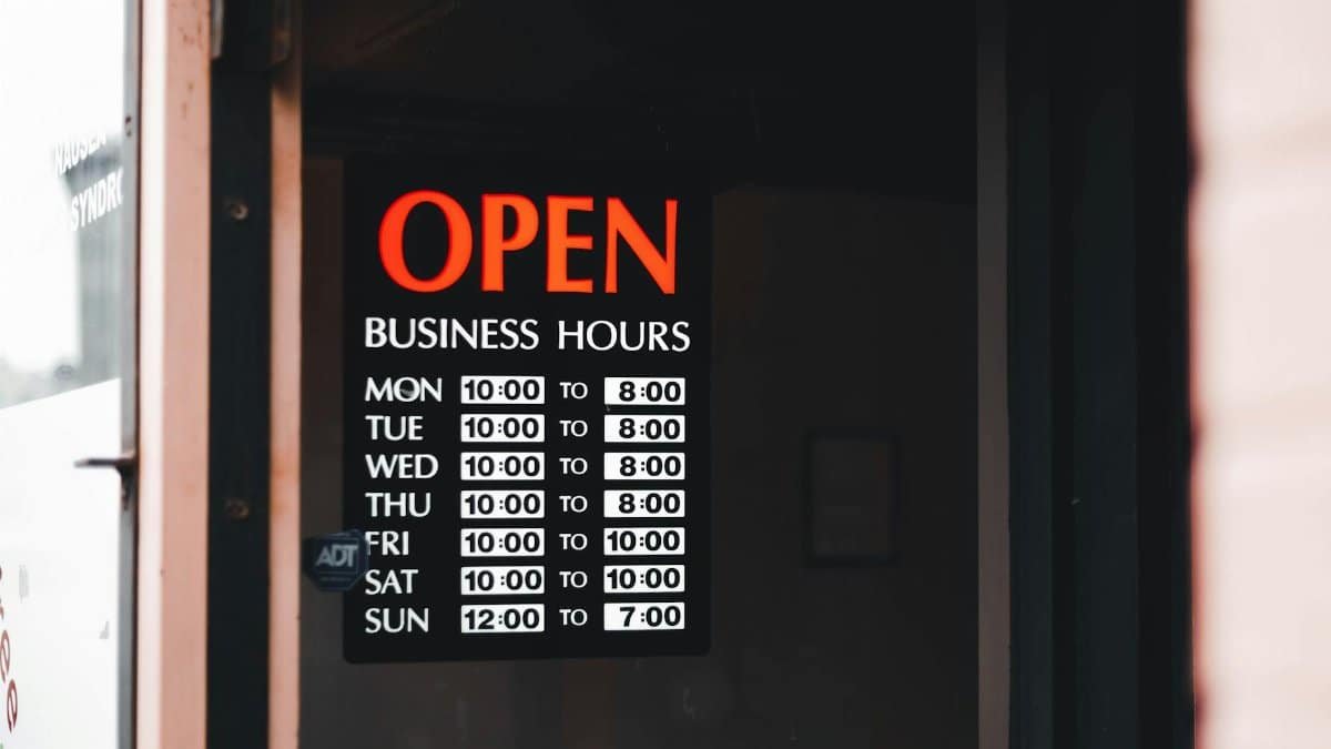 Close-up of an open business hours sign displayed in a shop window.