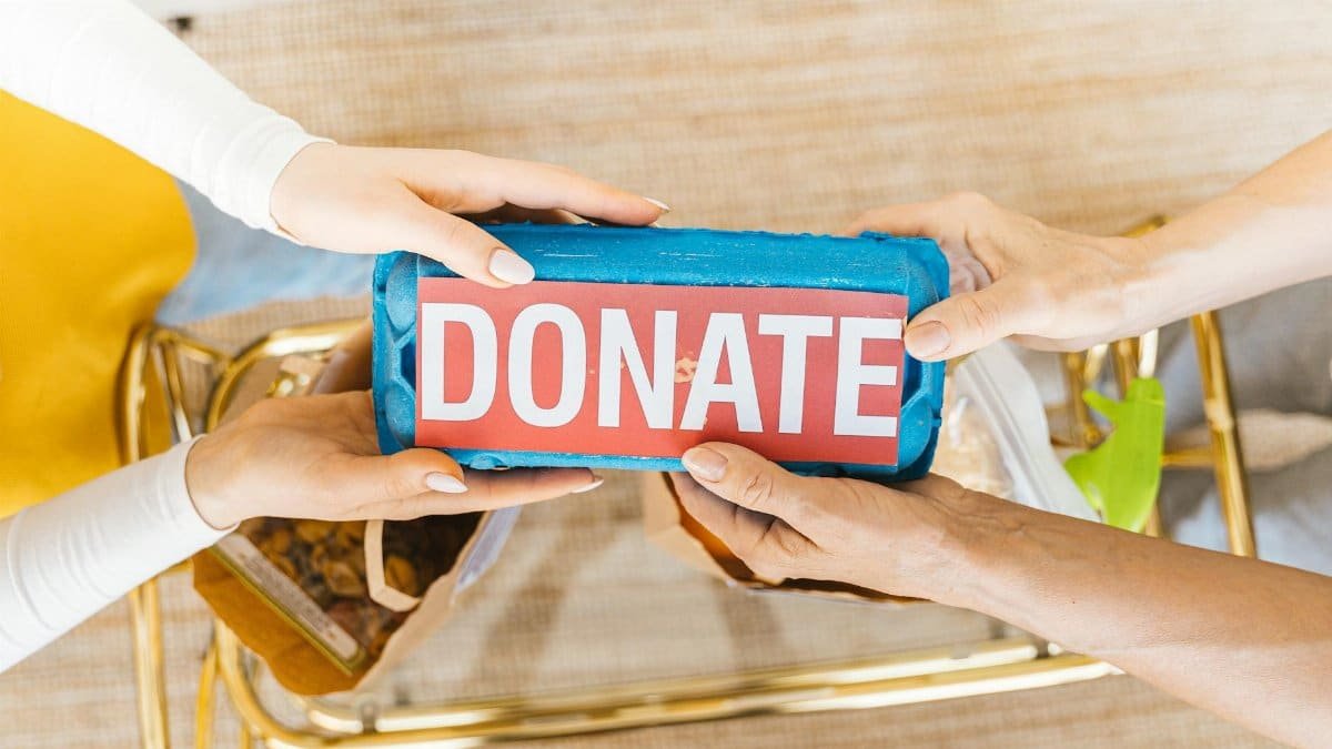 Hands exchanging a donation box filled with items, symbolizing giving and community support.