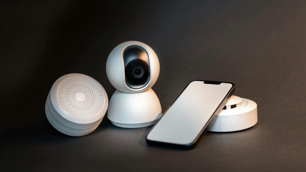 A sleek smartphone with modern smart home devices on a minimalist gray background.