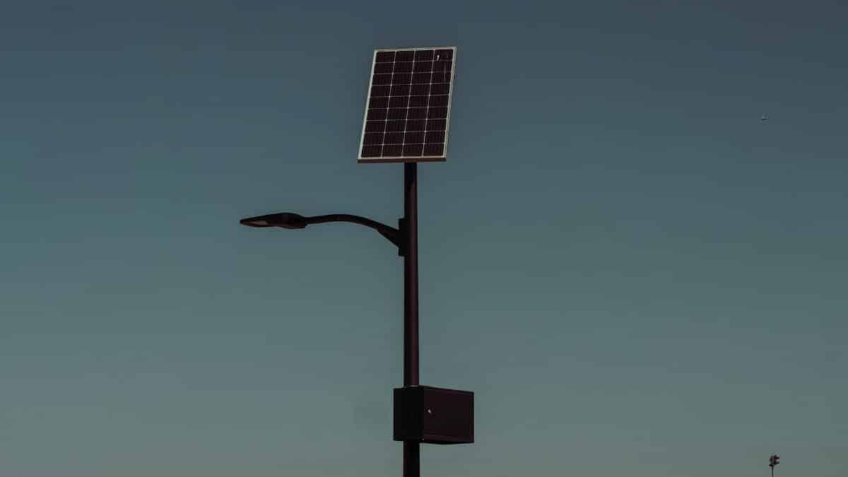 Street light with solar panel against a dusky sky, symbolizing renewable energy.