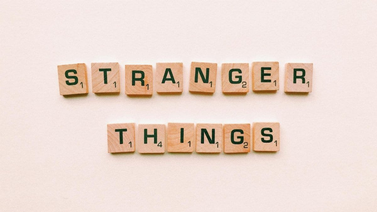 Artistic arrangement of Scrabble tiles spelling 'Stranger Things' on a minimalist background.