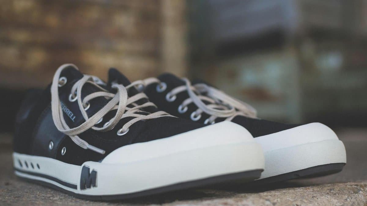 Casual black and white sneakers positioned on a rustic stone surface, showcasing classic style.