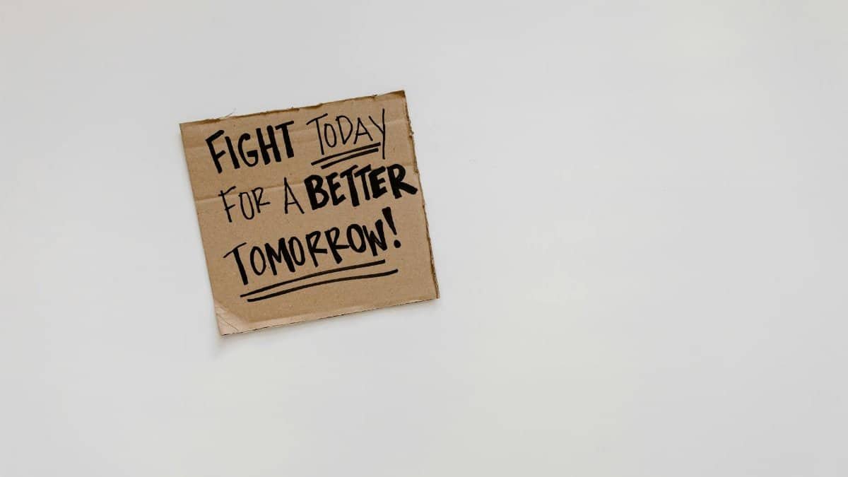 Cardboard sign with motivational quote: 'Fight today for a better tomorrow!' on white background.