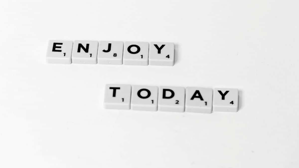 Close-up of letter tiles spelling 'Enjoy Today' on a white background, conveying positivity.