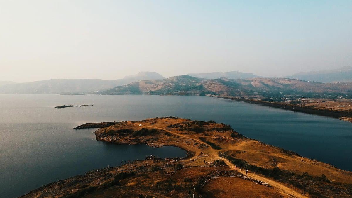 A stunning aerial view of a peaceful lake surrounded by rolling hills at dawn, showcasing natural beauty and tranquility.