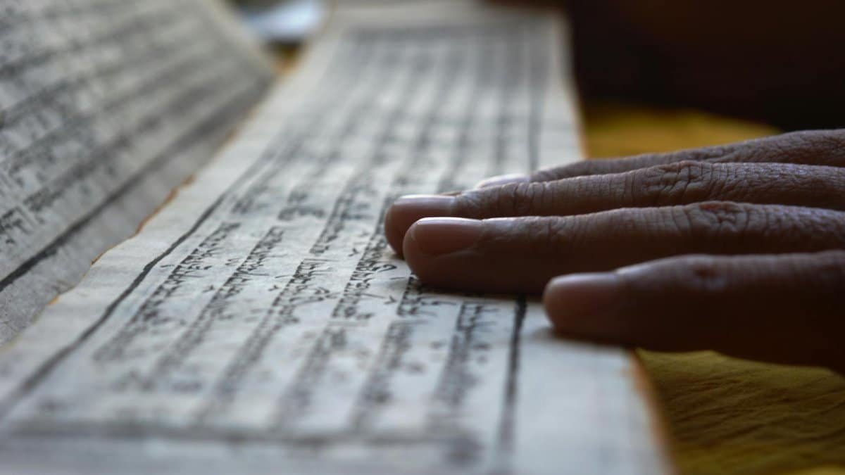 Hands gently rest on Buddhist scripture in Sikkim, reflecting spiritual focus and meditation.
