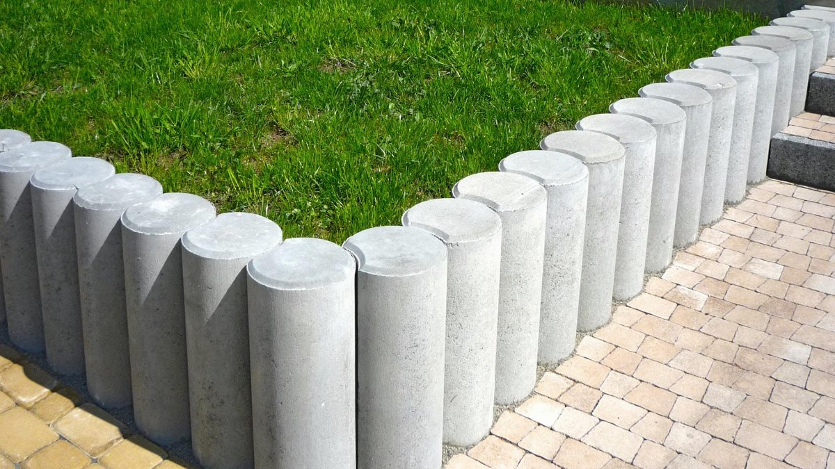 Cylindrical concrete blocks form a stylish lawn boundary, enhancing garden aesthetics.