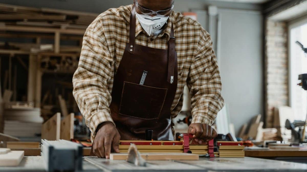 Portrait of a craftsman focused on precise woodcutting using tools in a workshop.