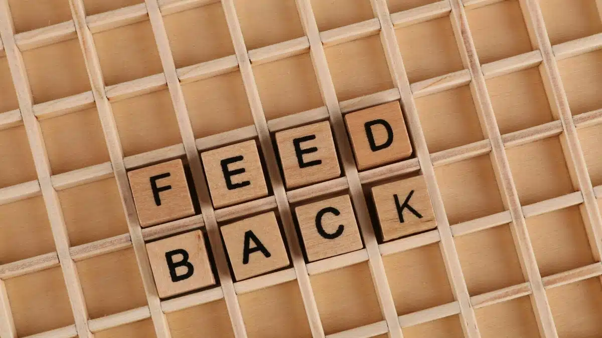 Wooden letter blocks spelling 'Feedback' on a wooden grid surface.