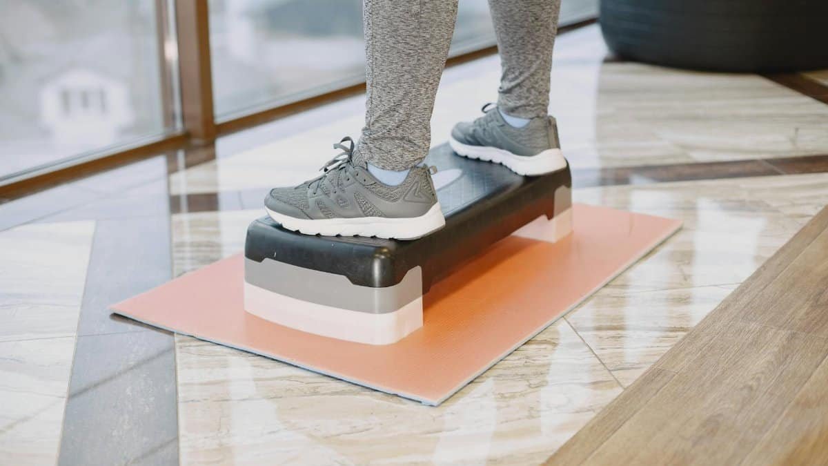 A person exercising indoors using a step platform for a workout routine.