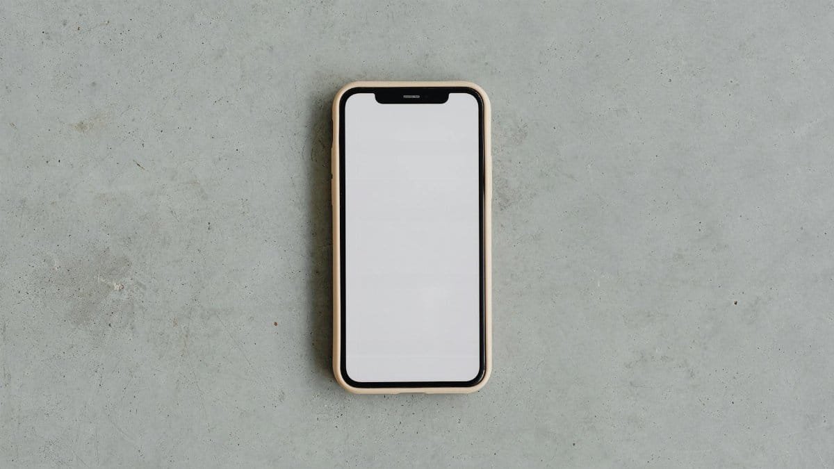 Top view of a modern smartphone with a blank white screen on a gray concrete background, ideal for mockups.