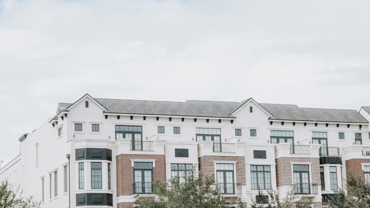 A stylish, multi-story luxury apartment building with a contemporary facade against a clear sky.