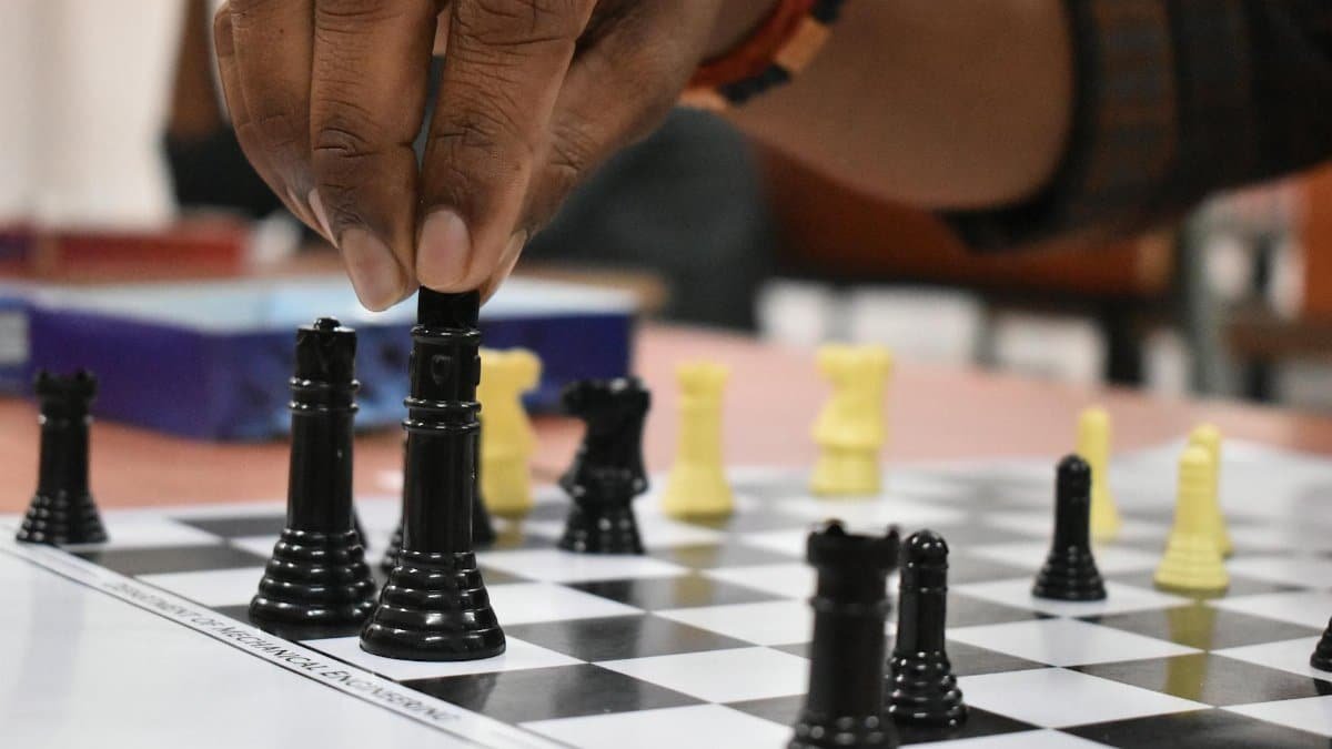Strategic chess move being made by a hand during a game indoors.